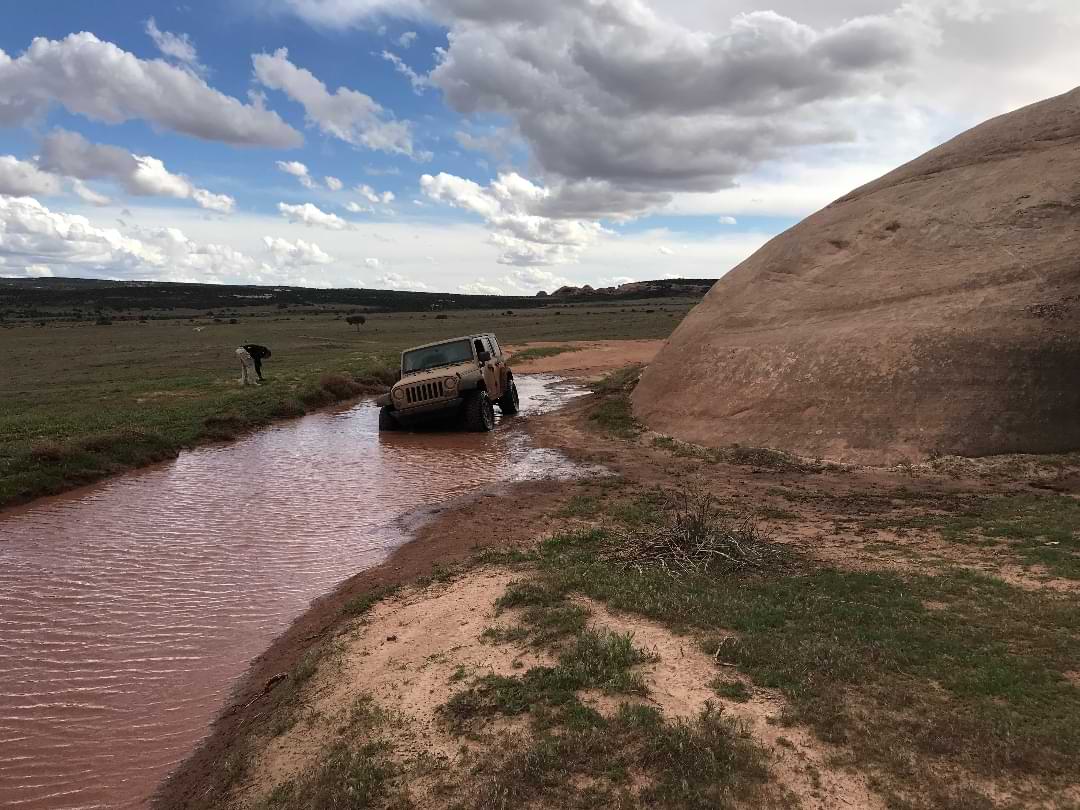Jeep crossing muddy trail water in Utah