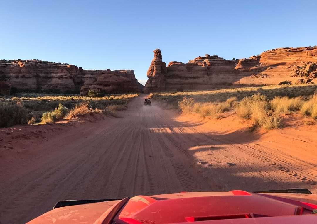 Offroad drive into the Utah desert at sunset, raising dust along the trail