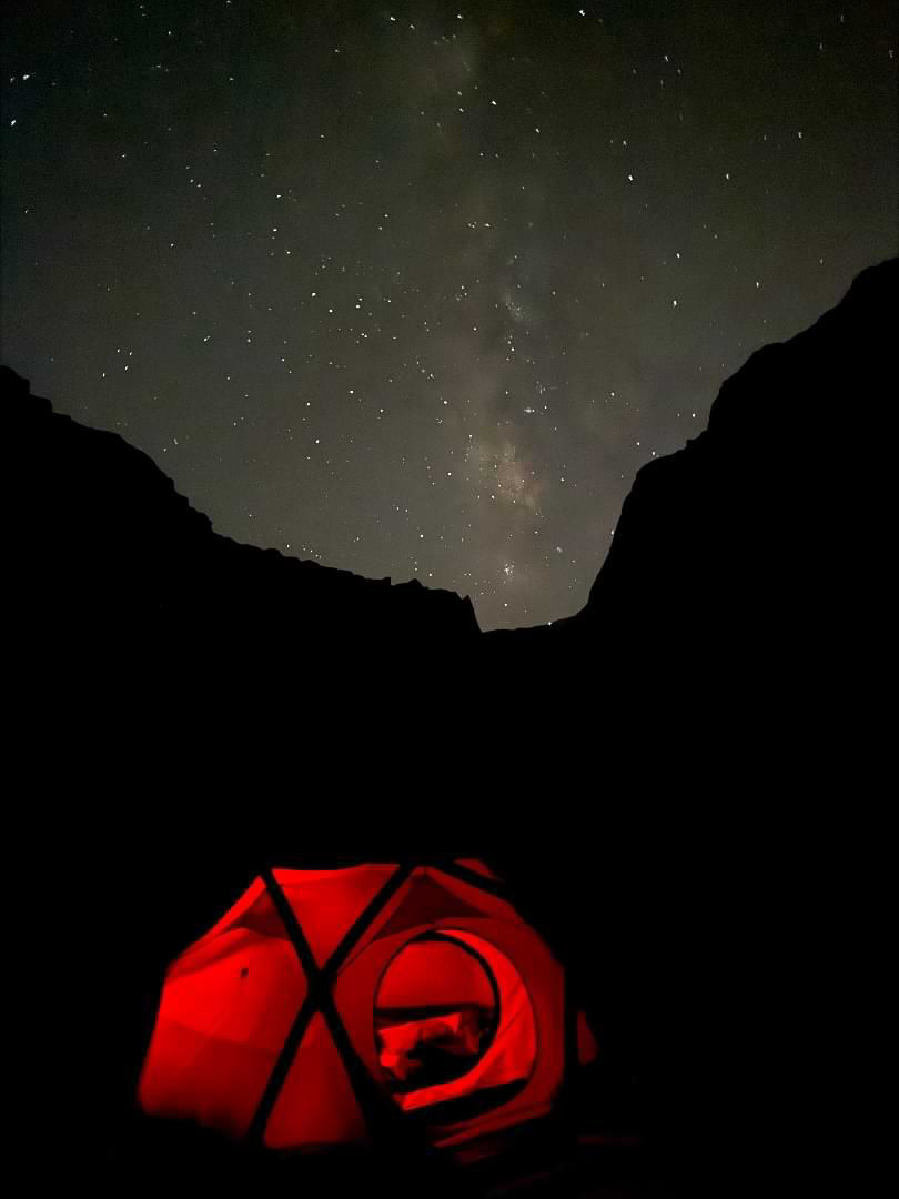 Glowing tent under a starry night sky in a remote canyon camp in the Southwest