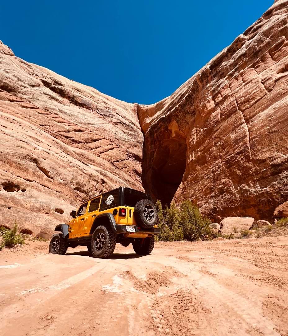 Yellow Jeep on sandstone trail in canyon