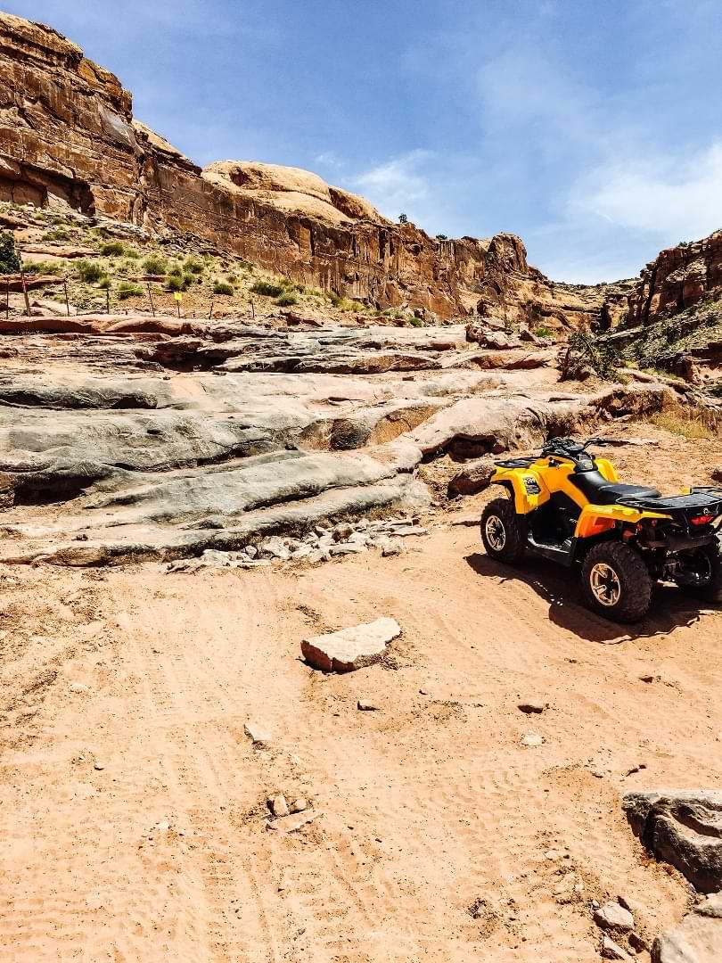 Yellow ATV parked near rock ledges on Utah trail